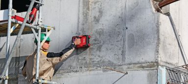 Trabajador utilizando una herramienta eléctrica para alisar una pared de concreto.