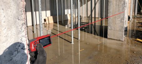 Dispositivo láser mide distancias en una construcción con varillas de refuerzo.