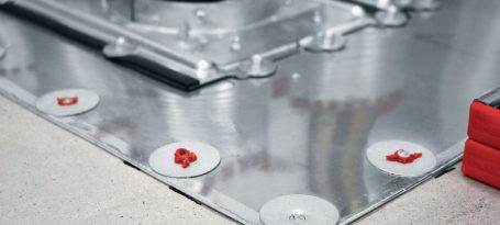 Superficie metálica con sellos rojos en el borde y cables visibles.