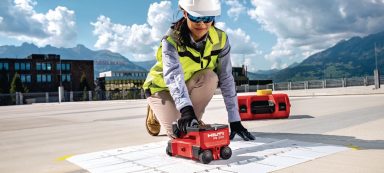 Persona midiendo superficies con un dispositivo pequeño en un sitio de construcción.