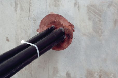 Tuberías negras unidas a una base circular en una pared de concreto.