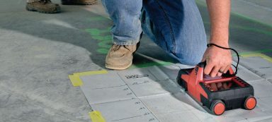 Persona utilizando una herramienta de línea láser para marcar el suelo en una construcción.