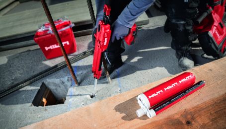 Herramienta de sellado roja en uso sobre una superficie de trabajo, con tubos de sellador.