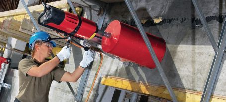 Hombre usando una herramienta hidráulica roja en un entorno de construcción.