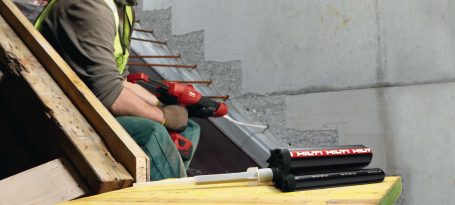 Trabajador usando una herramienta eléctrica en una construcción, con enfoque en la tarea.