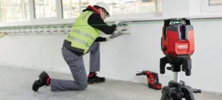 Trabajador midiendo una pared con láser en un sitio de construcción.
