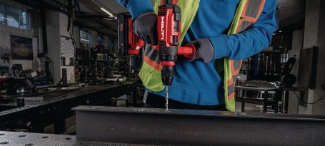 Persona usando un taladro eléctrico sobre una superficie de metal en un taller.