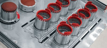 Rejillas metálicas con bordes rojos en una superficie de acero inoxidable.